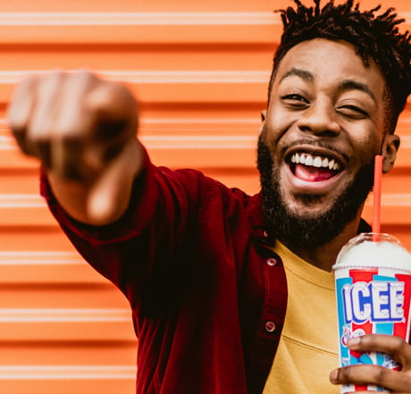 A man pointing and smiling while holding an ICEE