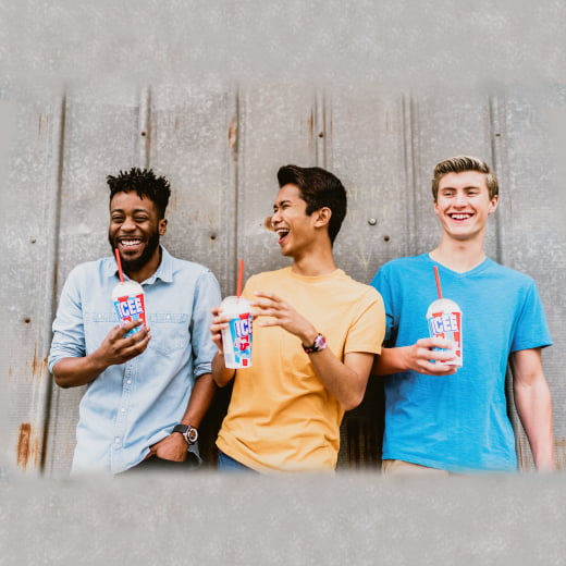 Three young men laughing while drinking ICEE's